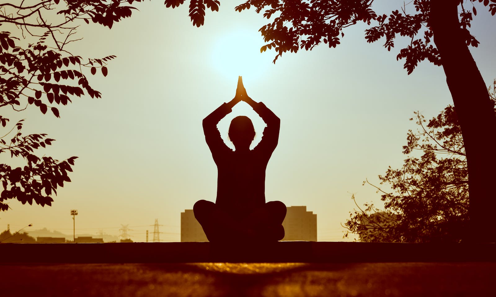Silhouette meditating at golden sunset—calm and emotional balance