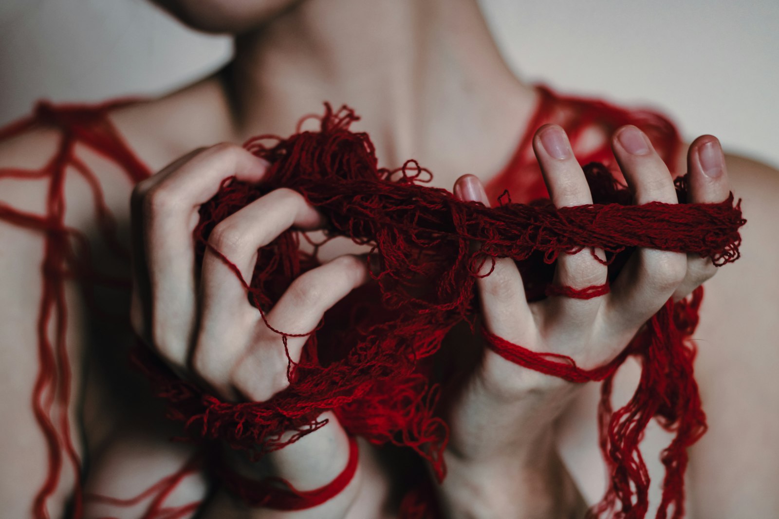 Hands gently working through tangled red thread—a metaphor for untangling relationship trauma